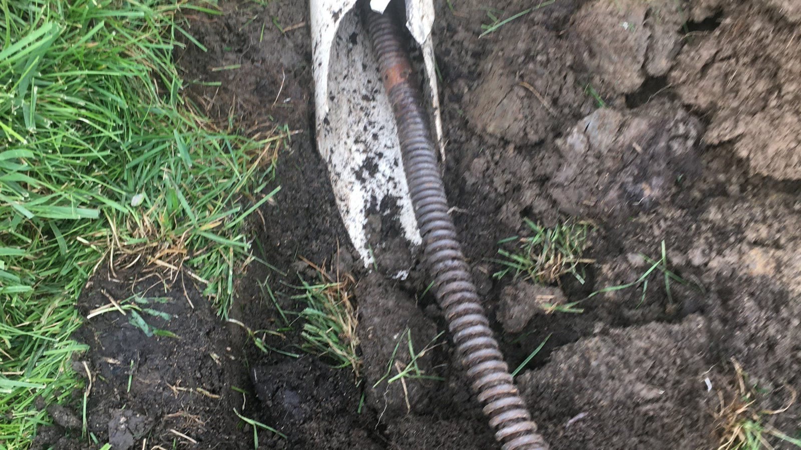 Drain line exposed in a trench during plumbing repair work